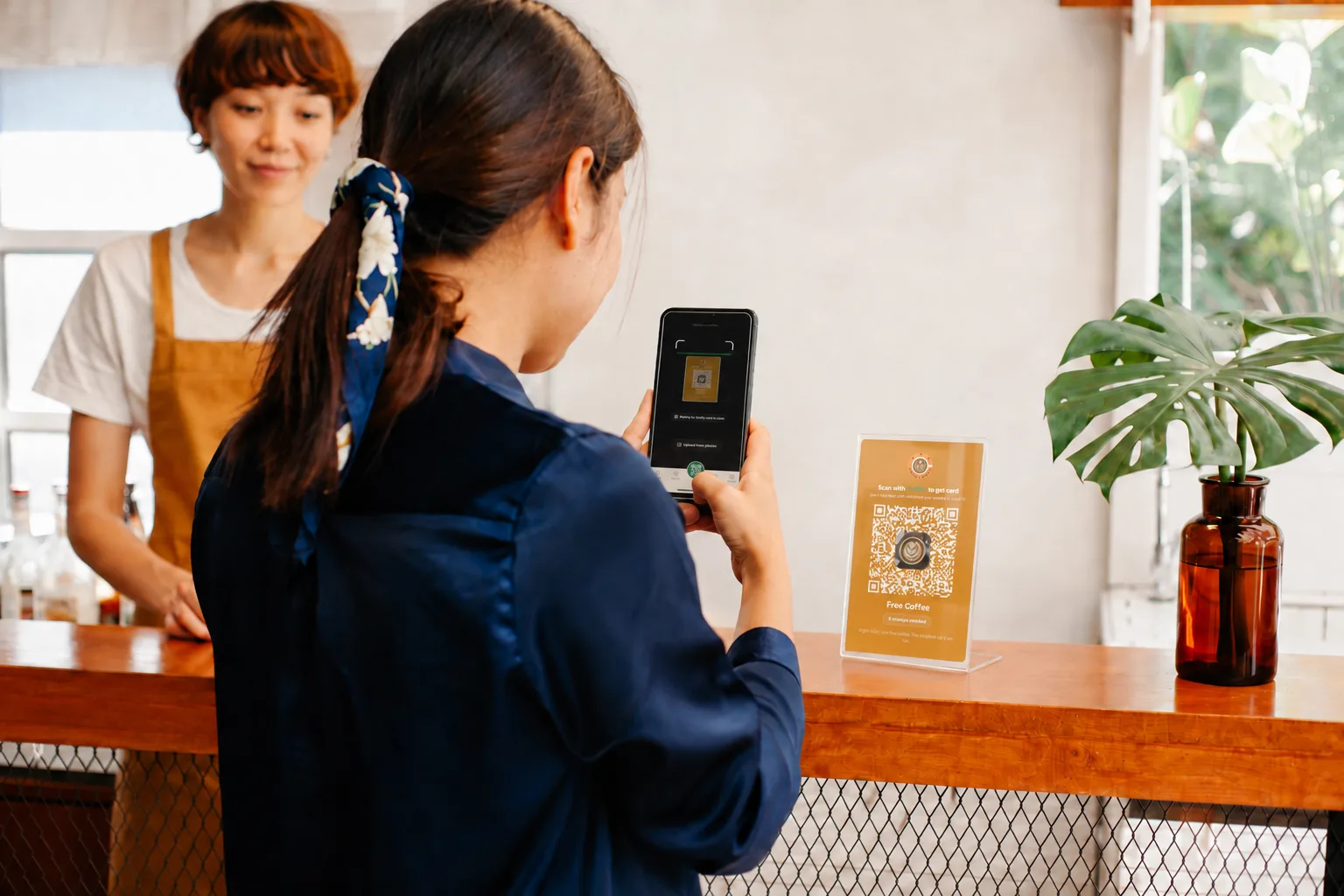 A customer scanning the Bean & Brew loyalty standee with the Sukify app