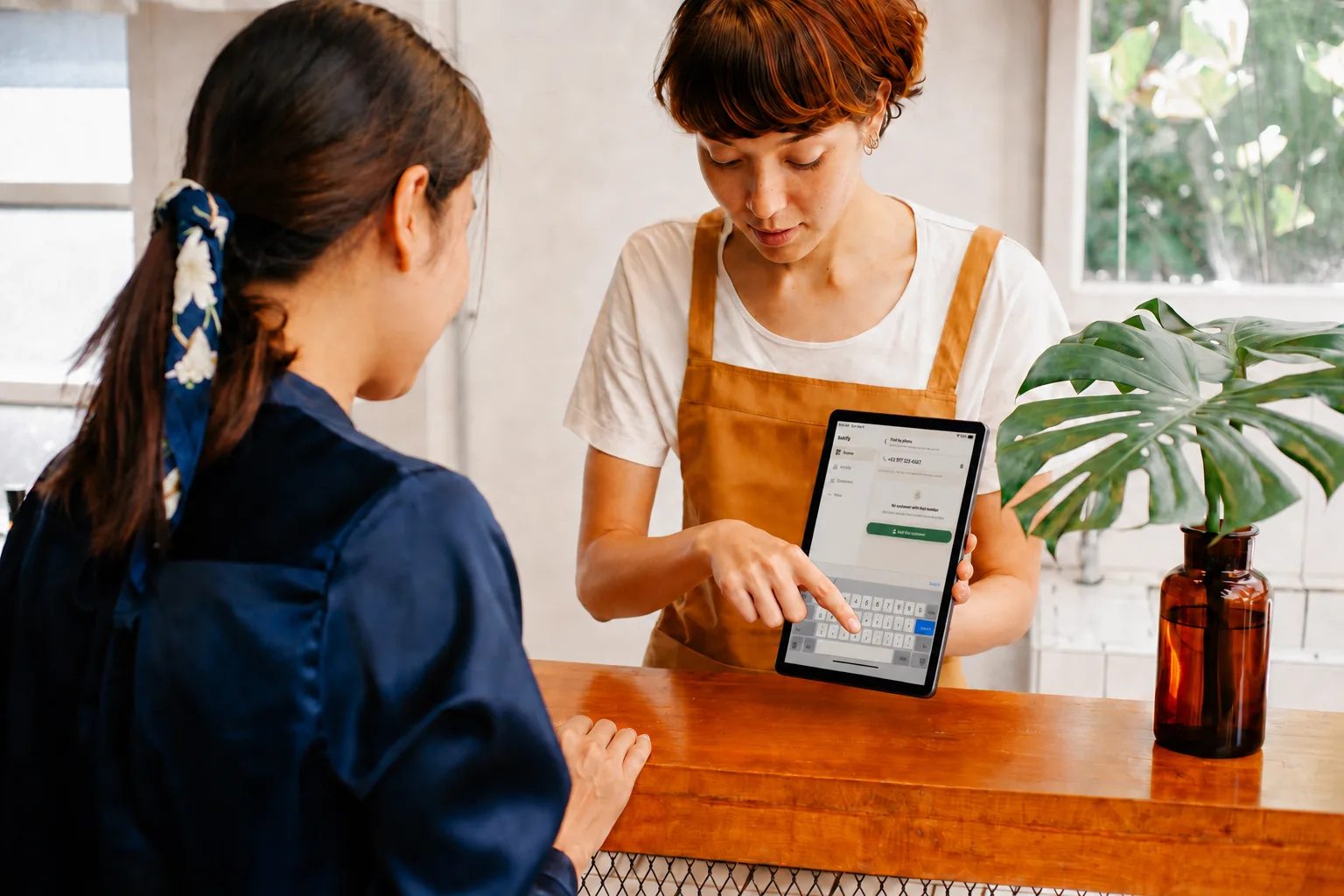 A clerk entering a phone number on a tablet
