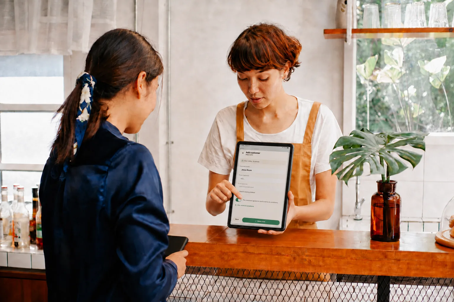 A clerk preparing a Bean & Brew Free Coffee card for Jessa Reyes on a tablet